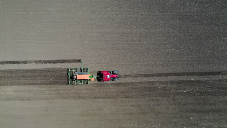 Red-tractor-driving-in-the-farm-field-filmed-from-above