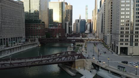 CTA-Train-Crossing-Chicago-River-as-Drone-Flies-over-Bridge,-Low-Angle