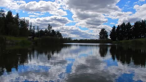 Blue-lakeside-water-mirror-reflection-bright-scenic-cloudy-sky