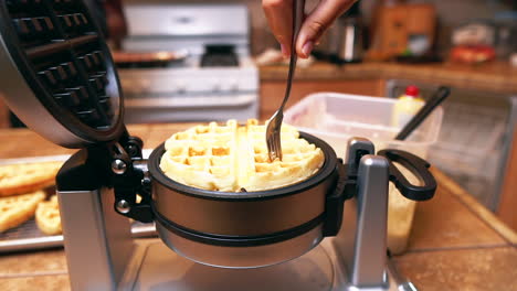 Pulling-a-fresh,-hot,-golden-brown-Belgian-waffle-off-the-iron---isolated-slow-motion