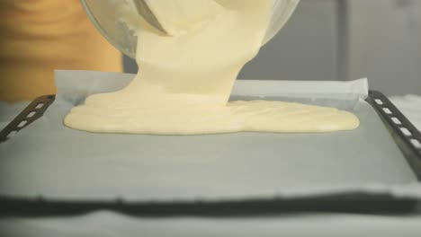 Close-up-of-a-cake-dough-being-put-on-a-baking-plate-with-a-backing-sheet-by-a-vegan-chef