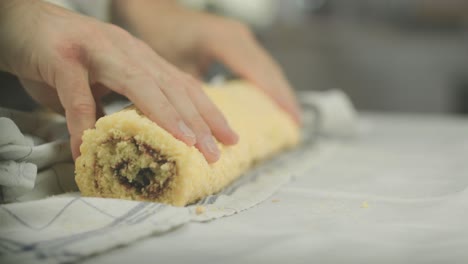 Chef-removes-towel-from-a-freshly-baked-and-rolles-swiss-roll-vegan-desert-with-jelly-jam-in-the-middle