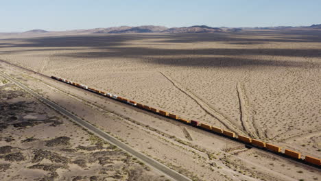 Extremely-long-freight-train-with-hundreds-of-train-cars-speeds-down-a-straight-train-track-in-the-desert