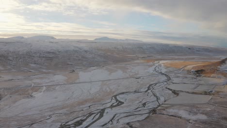 Drone-Flies-over-Awe-Inspiring-Rivers-running-through-Uninhibited-Icy-Westfjords-Valley-with-frozen-rivers-during-Cold-Winter,-Aerial-in-Iceland,-Snowy-Winter-wonderland