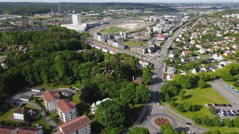 Drone-Volando-Sobre-Los-Frondosos-árboles-Y-Edificios-De-Apartamentos-En-Frolunda,-Gotemburgo,-Suecia-Con-Vehículos-Que-Viajan-Por-La-Carretera-En-Un-Día-Soleado---Antena