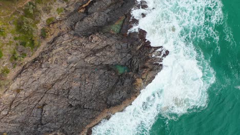 Aerial:-people-swimming-in-coastal-rock-pools-beside-turquoise-ocean-water-waves