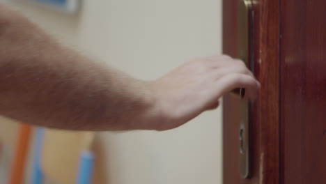 A-Male-Arm-Tries-to-Pull-Open-a-Locked-Wooden-School-Door-with-a-Heavily-Used-Brass-Handle,-Close-Up