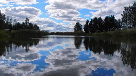 Blue-lake-water-mirror-reflection-bright-scenic-cloudy-sky-tranquil-scene
