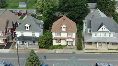 Aerial-establishing-shot-of-colonial-two-story-homes-in-American-small-town,-man-crosses-road-as-truck-passes-by,-United-States-of-America,-USA