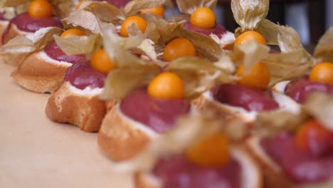 Picturesque-colorful-buffet:-Close-up-of-many-biscuits-with-a-cherry-topping-and-physalis-on-top