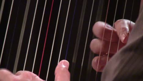 Close-up-of-hands-playing-the-harp-and-plucking-strings-with-a-blurred-background