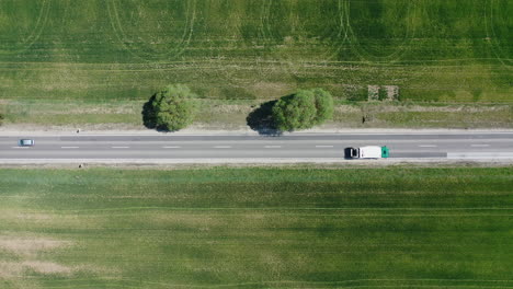 Steady-drone-shot-of-a-2-lane-highway-with-cars-and-trucks-driving-by