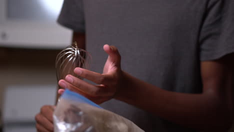 Young-African-American-man-holds-a-whisk-and-is-ready-to-help-stir-ingredients-together