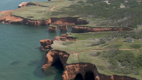 Sea-Stacks-And-Red-Cliffs-Of-The-Magdalen-Islands-With-Green-Fields-And-Trees-By-The-Saint-Lawrence-River-In-Quebec,-Canada