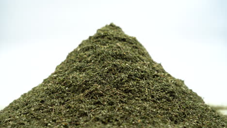 Push-In-Shot-of-Pile-Dried-Cannabis-Leaves-in-Studio-with-White-Background