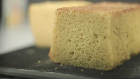A-chef-testing-the-consistency-of-a-freshly-baked-sponge-cake,-with-a-sliced-peace-of-cake-lying-in-the-focal-point