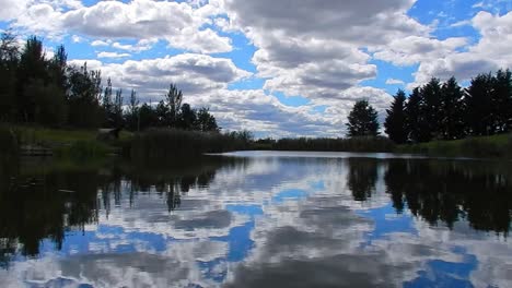 Blauer-Friedlicher-See-Wasserspiegelreflexion-Heller-Szenischer-Bewölkter-Himmel