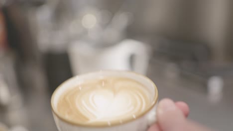 Barista-Gießt-Langsam-Eine-Tasse-Milch-In-Eine-Cappuccino-Tasse-Kaffee-Und-Bildet-Ein-Cremeweißes-Herz-Auf-Der-Oberfläche-Des-Kaffees