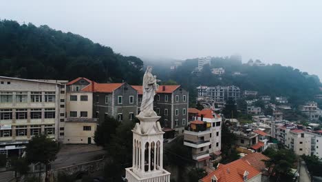 Aerial-drone-view-of-virgin-Mary-statue-in-Dhour-El-Choueir,-Lebanon,-misty-day