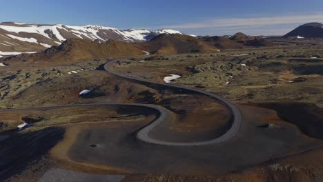 Winding-Road-By-The-Lava-Field-Overlooking-The-Icelandic-Mountains-Partly-Covered-In-Snow-During-Summer-In-Iceland