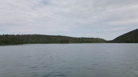Überfliegen-Des-Ruhigen-Wassers-Des-Verlorenen-Sees-Mit-Einem-Malerischen-Blick-Auf-Den-Grünen-Wald-Und-Den-Hellen-Himmel-Auf-Der-Gaspesie-Halbinsel,-Quebec,-Kanada