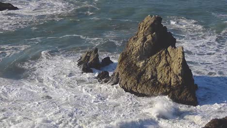 Powerful-Pacific-Ocean-waves-crashing-against-a-large-ocean-sea-stack-rock-formation-with-birds-sitting-on-top-of-it---San-Francisco,-California
