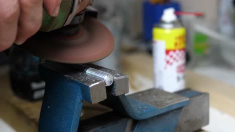 Professional-craftsman-use-angle-grinder-on-steel-bolt-inside-of-work-shop