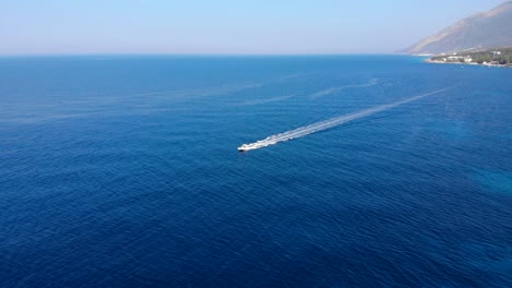 Motorboat-sailing-from-coastline-toward-deep-blue-sea-in-Mediterranean,-vacation-concept