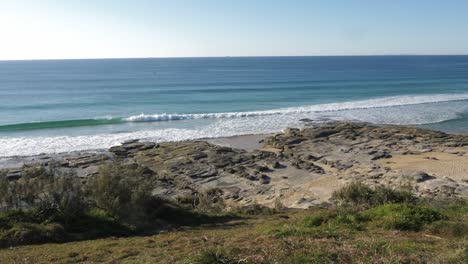 Beautiful-blue-waves-rolling-to-the-rocky-beach---Buddina-Port-Cartwright-Lighthouse---Sunshine-Coast-Australia---Slow-motion