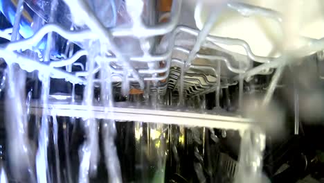 Inside-working-dishwasher,-cleaning-dishes-with-spraying-water,-GoPro