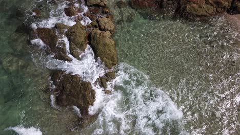 aerial-view-of-small-waves-crashing-on-coastline-rocks