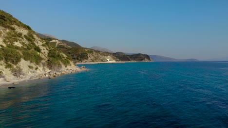 Blue-azure-sea-water-washing-rocky-shoreline-down-the-hills-on-a-sunny-day-in-Mediterranean