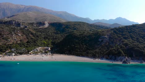 Beautiful-sunrise-over-beach-surrounded-by-green-hills-and-blue-azure-Ionian-sea-in-Albania