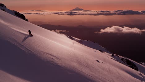 Epic-scene-of-two-freeriding-snowboarders-going-down-snowy-slope-during-dusk