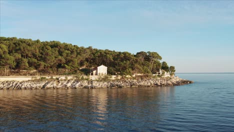Aerial-dolly-shot-over-the-water-pulling-up-and-over-a-house-in-Losinj,-Croatia-during-the-day