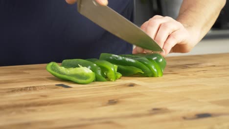 Grüne-Paprika-Auf-Einer-Holztischplatte-Mit-Einem-Kochmesser-Schneiden