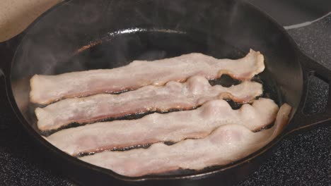 Cast-Iron-pan-on-stove-frying-bacon-cooking-hot-grease