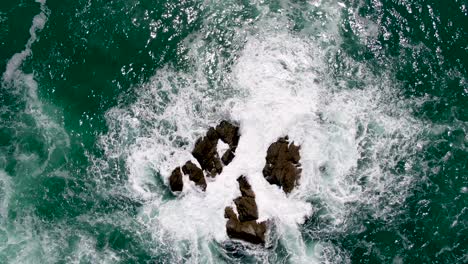 Rough-Ocean-Waves-Crashing-Against-Sharp-Rocks---Aerial-Overhead-View