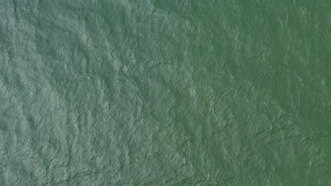 AERIAL:-Lifting-Up-Above-Green-Sea-With-Waves-Rippling-All-Over-the-Surface