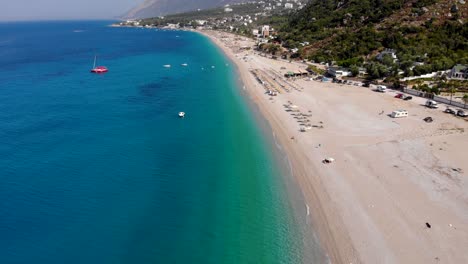 Amplia-Playa-De-Arena-Bañada-Por-Aguas-Tranquilas-Y-Claras-Del-Mar-Jónico-Azul-Celeste-En-La-Costa-Albanesa