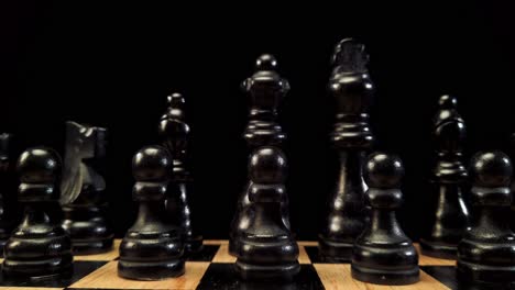 LKW-Aufnahme-Von-Rechts-Nach-Links-Mit-Schwarzen-Schachfiguren,-Die-Auf-Einem-Schachbrett-Auf-Schwarzem-Hintergrund-Stehen