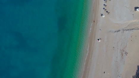 Beach-seen-from-above-with-white-pebbles-washed-by-blue-turquoise-lagoon-in-Mediterranean-sea