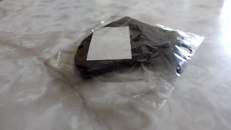 Black-mask-in-its-packaging-on-a-marble-counter,-no-persons