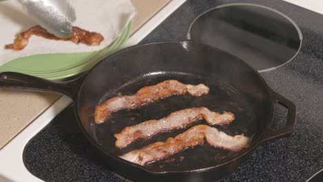 Cast-Iron-pan-on-stove-removing-bacon-from-hot-pan