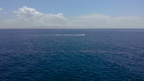 Meeresstrahlverfolgung-Durch-Tiefblaues-Meerwasser-Mit-Weißen-Wolken-Und-Hellem-Himmelshintergrund