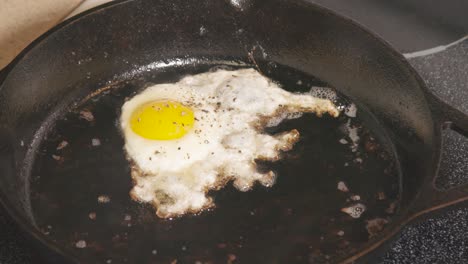 Cast-Iron-pan-on-stove-frying-egg-brown-edges-yellow-yolk