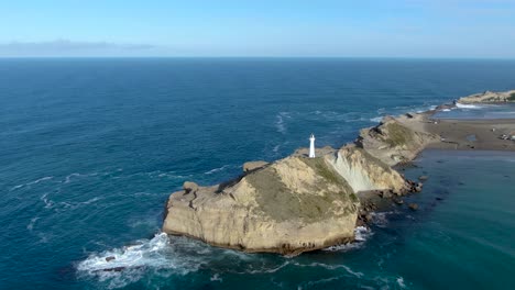 Castlepoint-Lighthouse-Tower-on-Rocky-Coast-of-North-Island,-New-Zealand---Aerial-Approaching-View