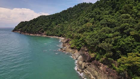 Drone-dolly-shot-of-jungle-coastline-with-small-beach-and-ocean