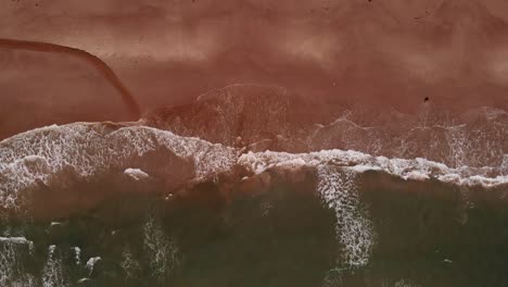 4k-Aerial-of-empty-sand-beach-with-wide-waves-while-slowly-moving-closer-to-the-shoreline