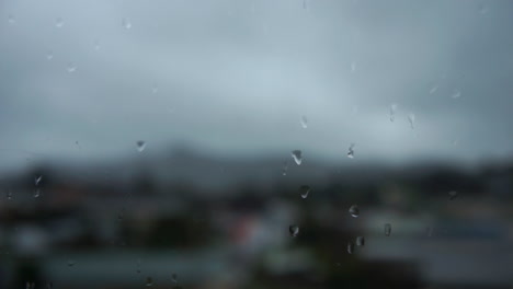 Close-Up-of-Rain-droplets-on-a-window-with-Cars-driving-out-of-focus-in-the-background